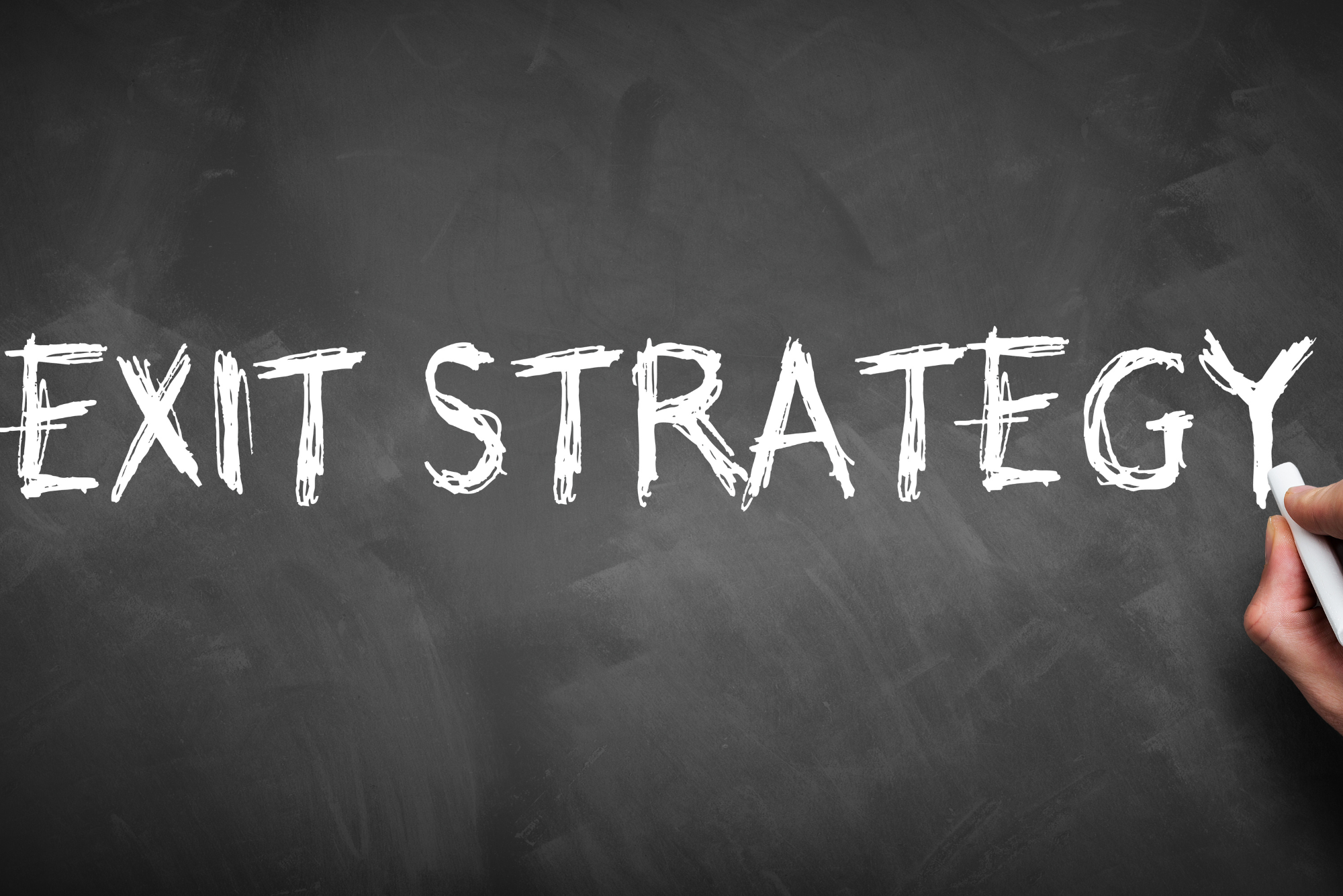 Handwriting the words “EXIT STRATEGY” in white chalk on a blackboard.