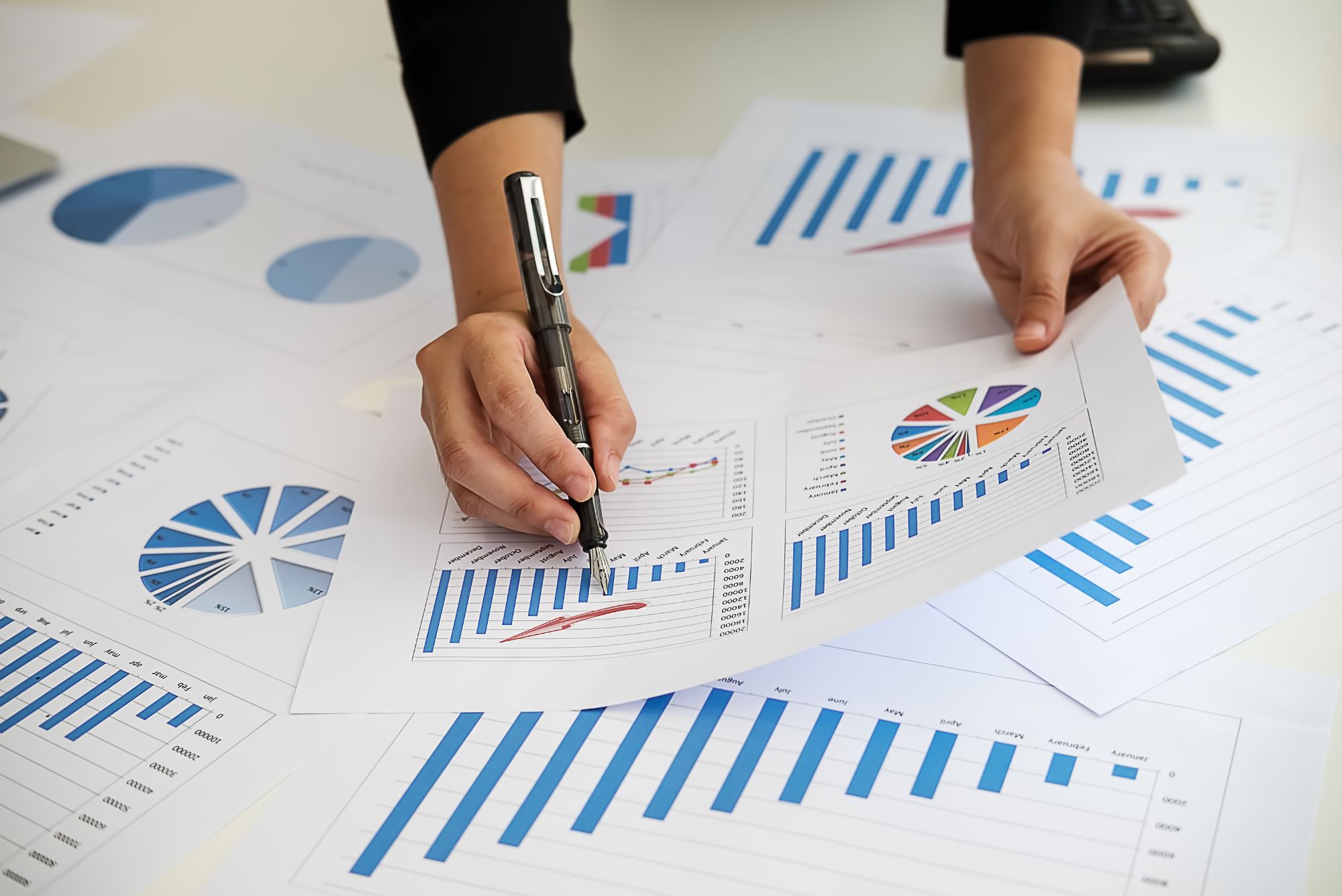 A businesswoman reviews graphs and charts spread across her desk as she develops her CapEx budget.
