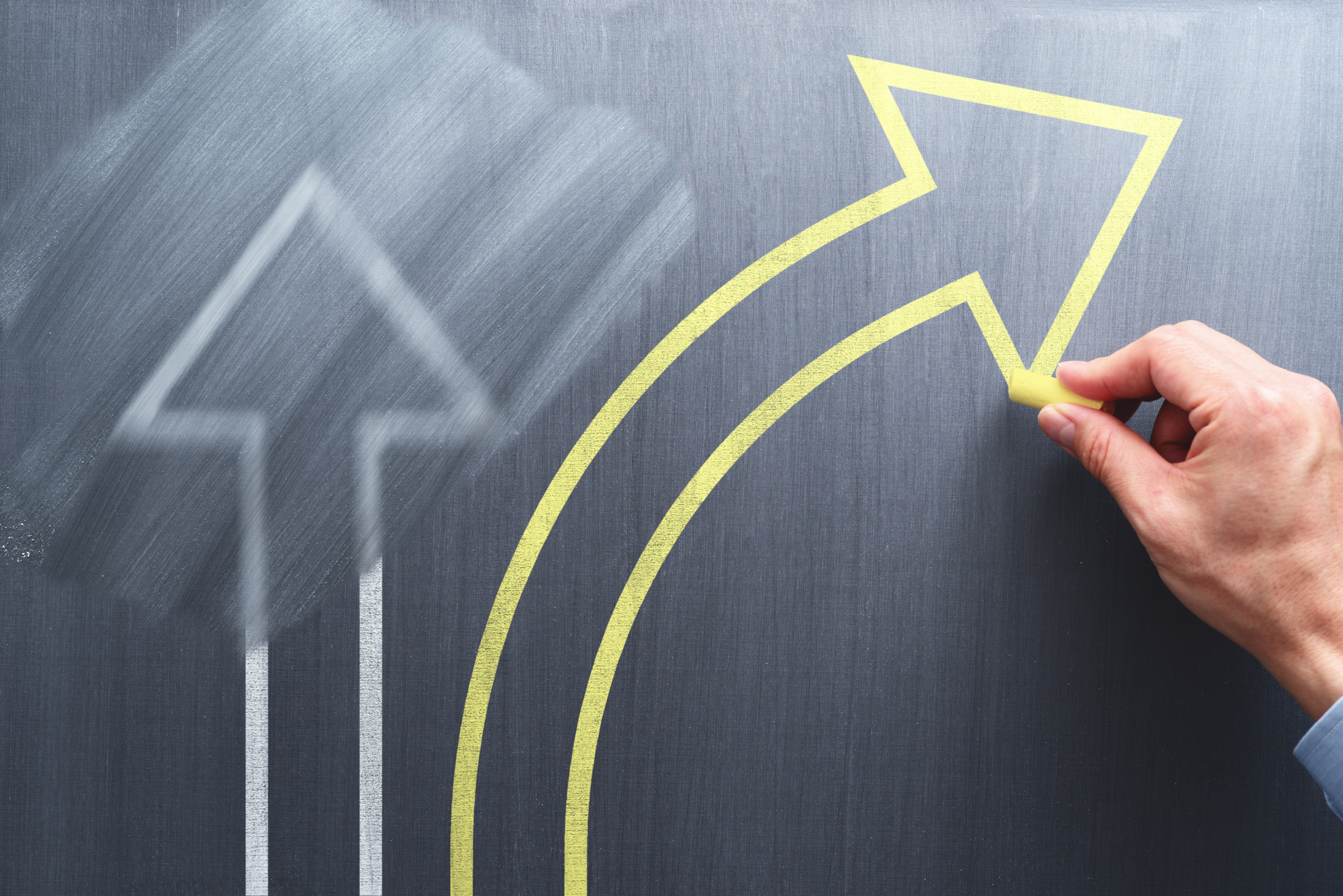 A yellow arrow veering off the to right on a chalkboard represents the idea of pivoting your business.