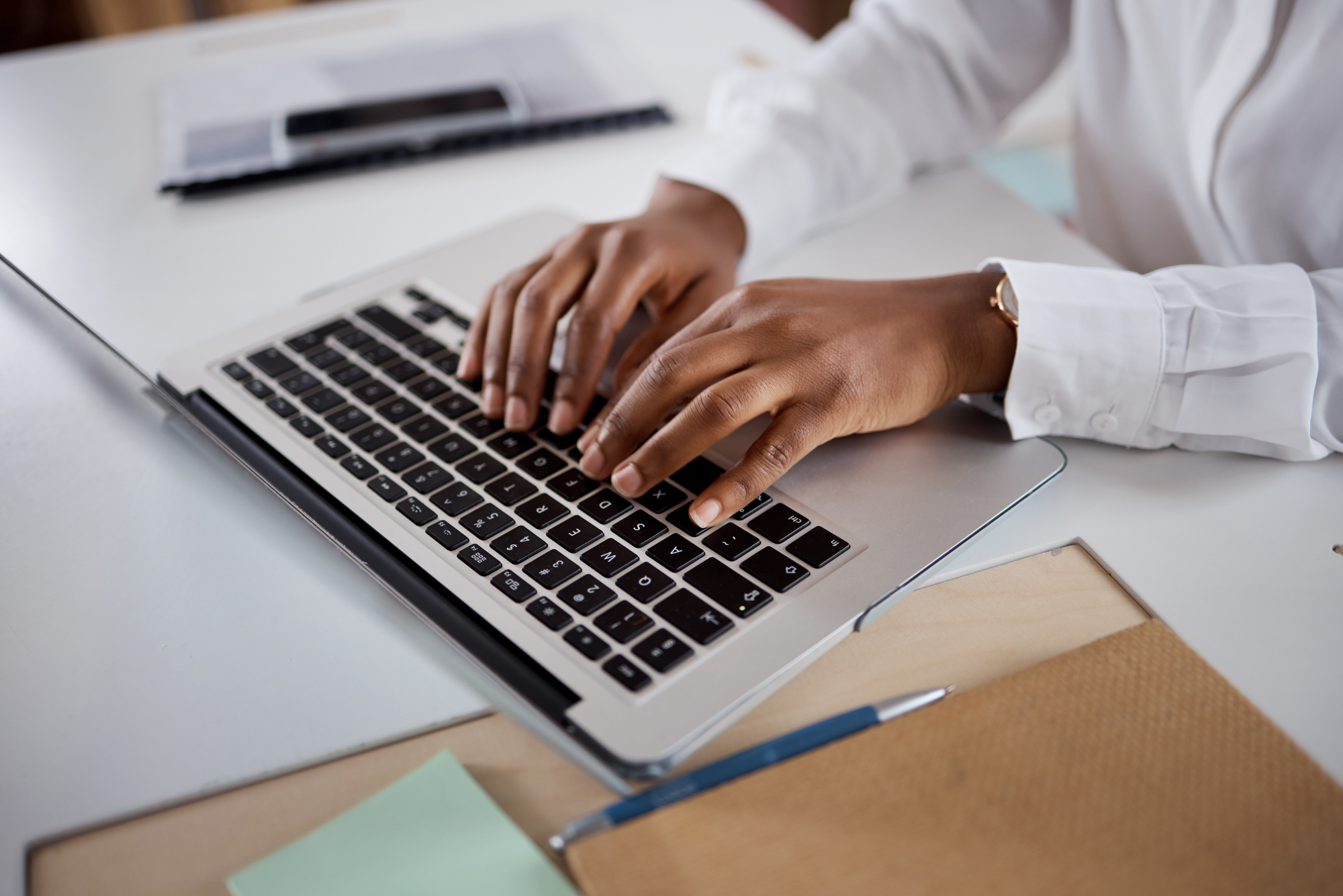 Close-up of a professional typing on a laptop at a desk.