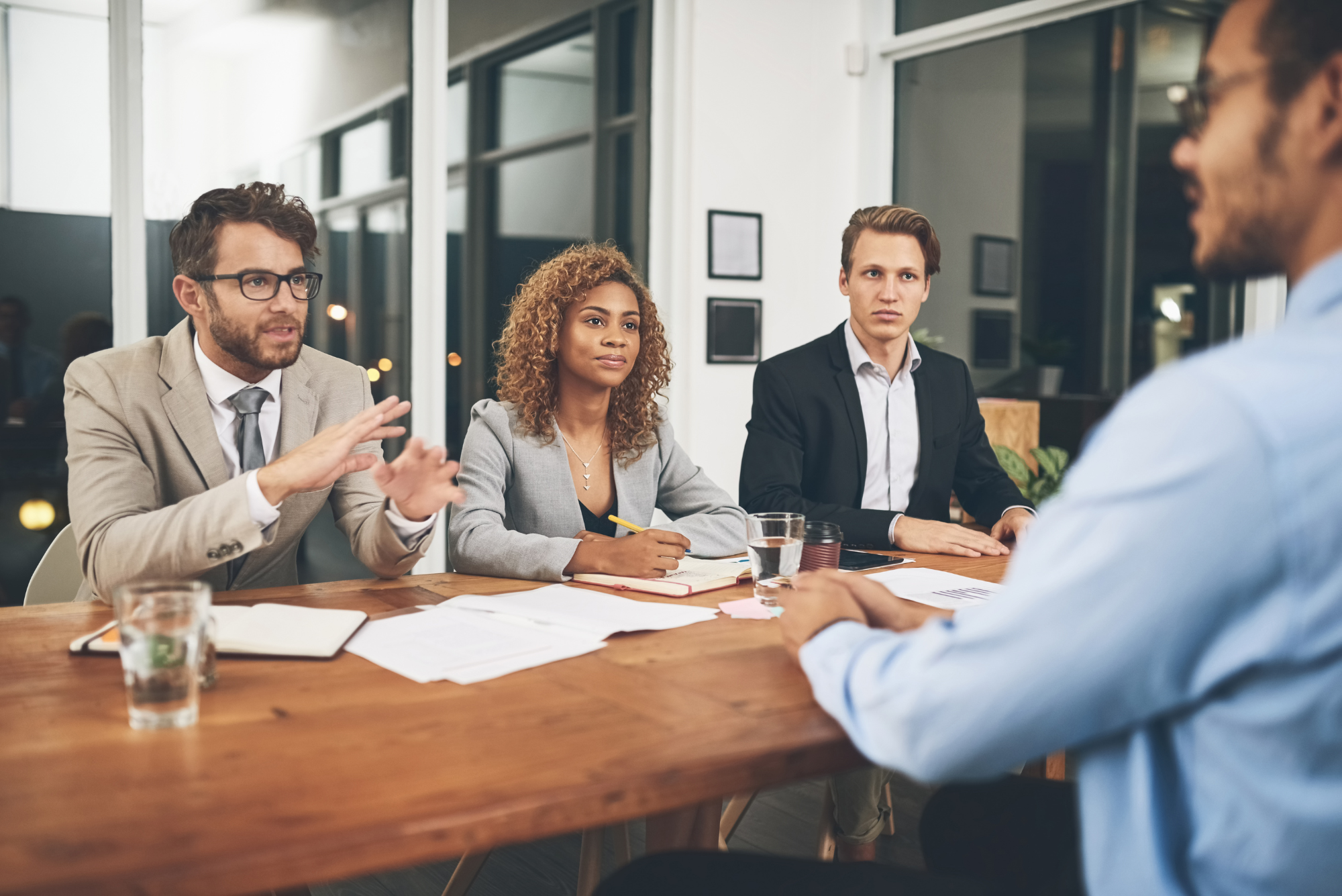 Job interview panel evaluating candidate across wooden conference table in modern office setting.