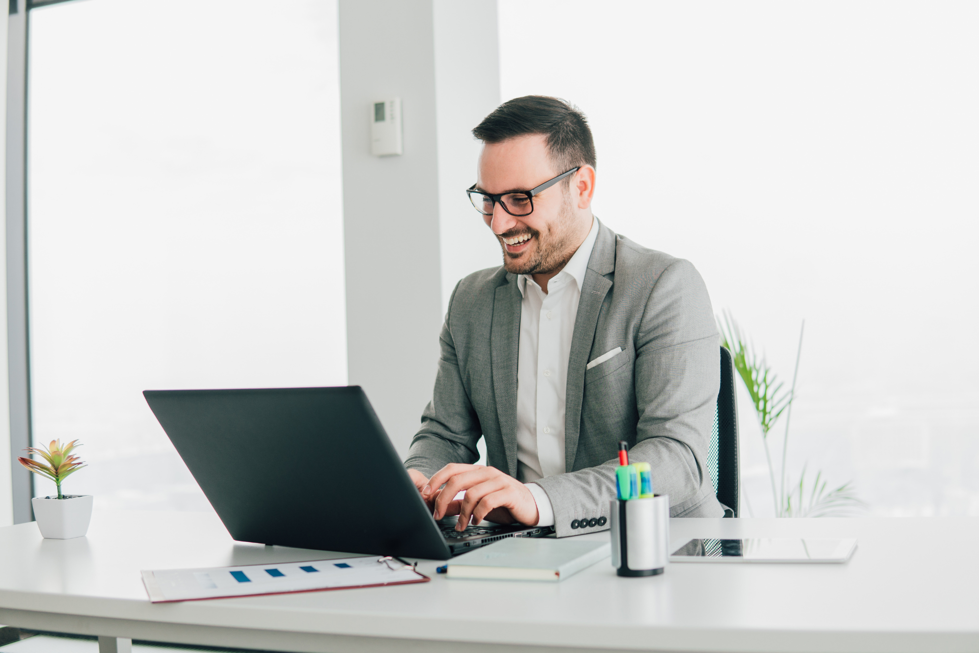 Thoughtful businessman working at laptop in modern office.