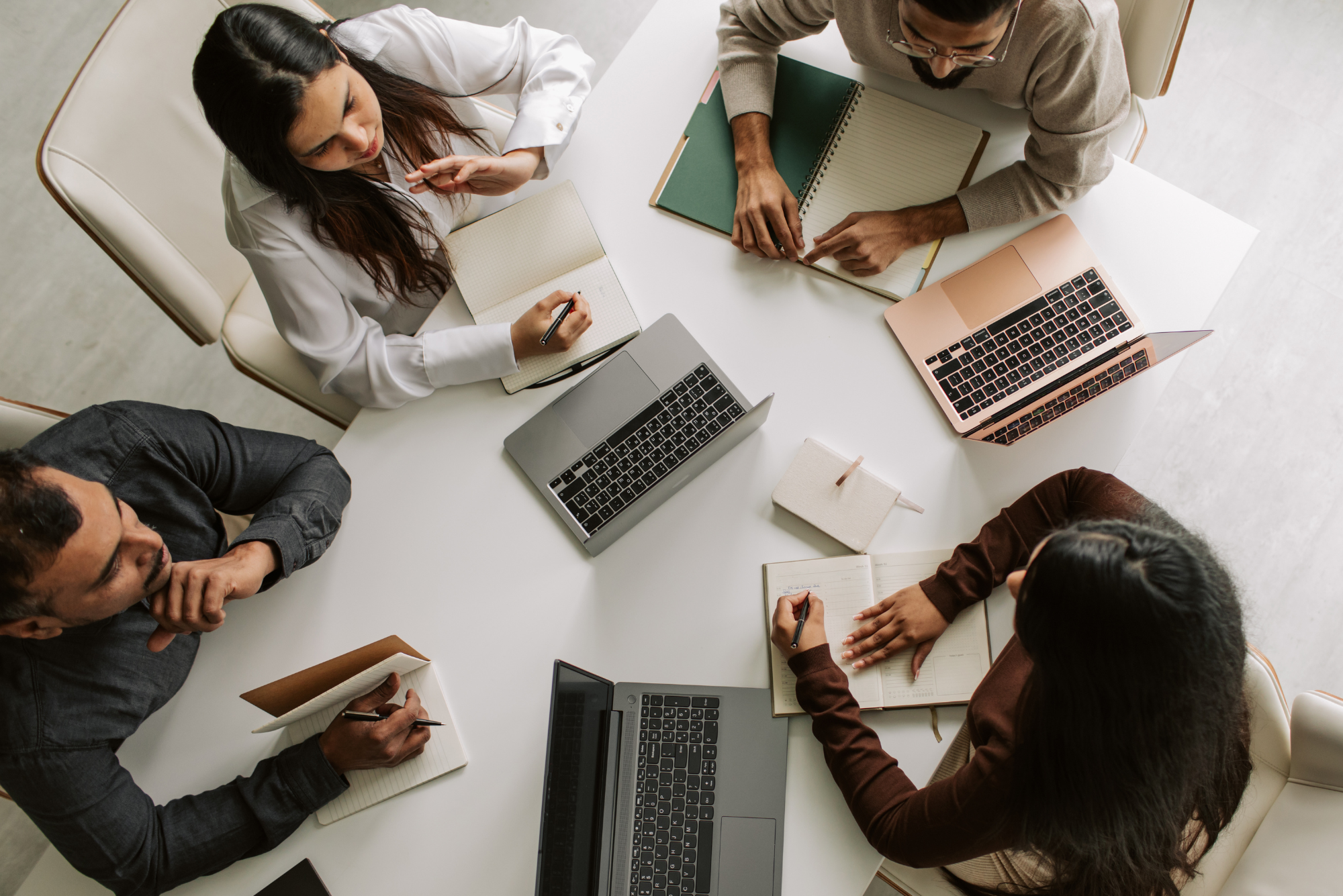 Diverse team of business professionals collaborating around laptops.