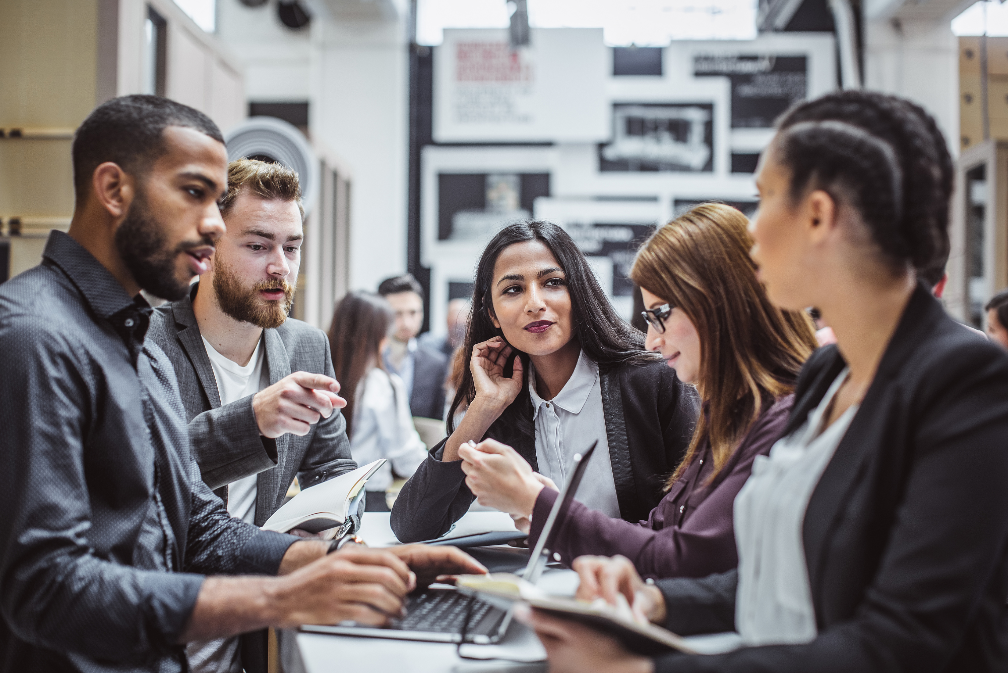 Group of people gathered around laptop having discussion.