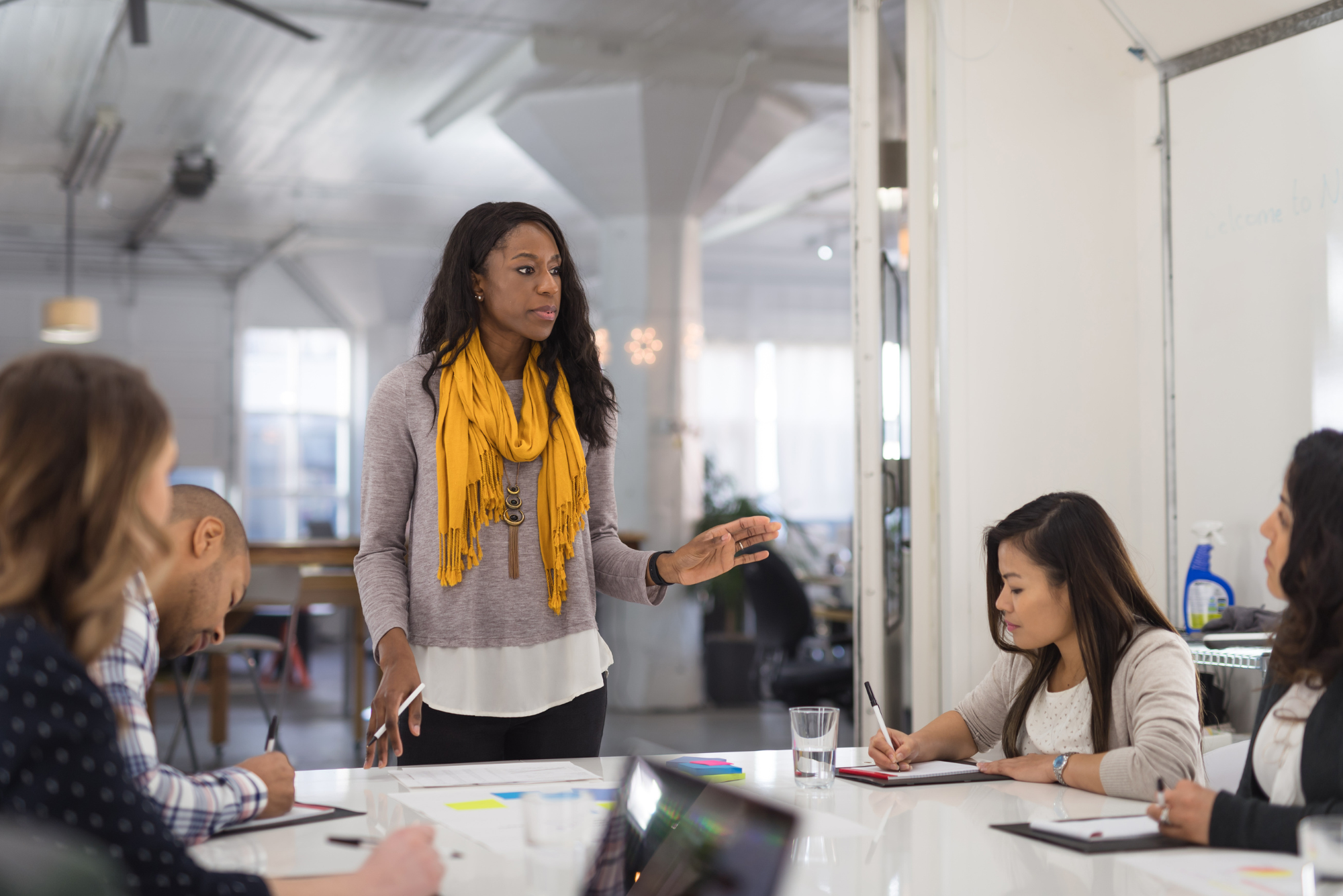 A woman leading a meeting at a whiteboard.