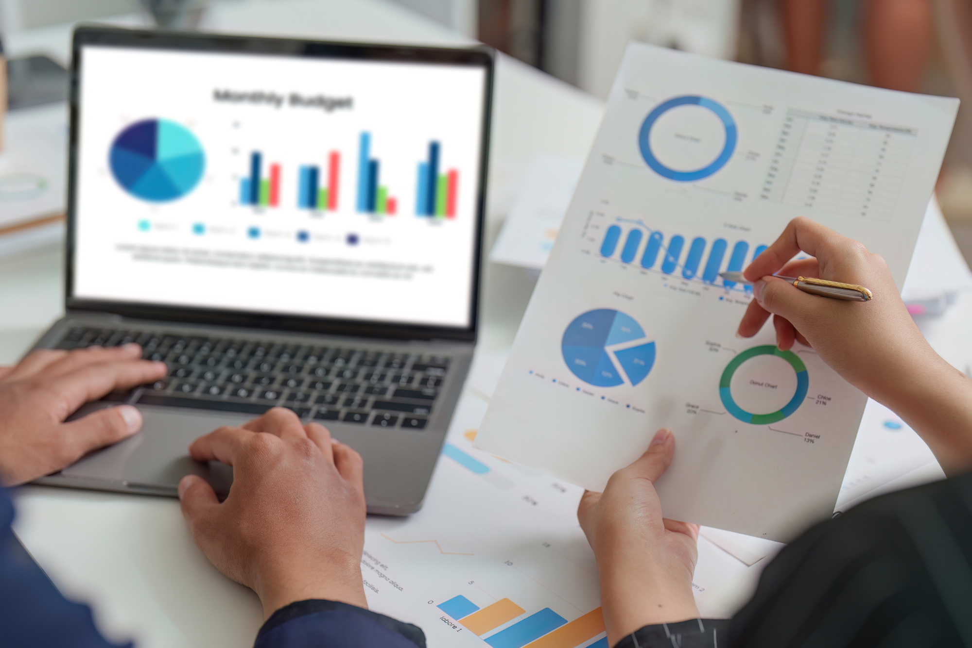 Two professionals reviewing monthly budget charts on a laptop.