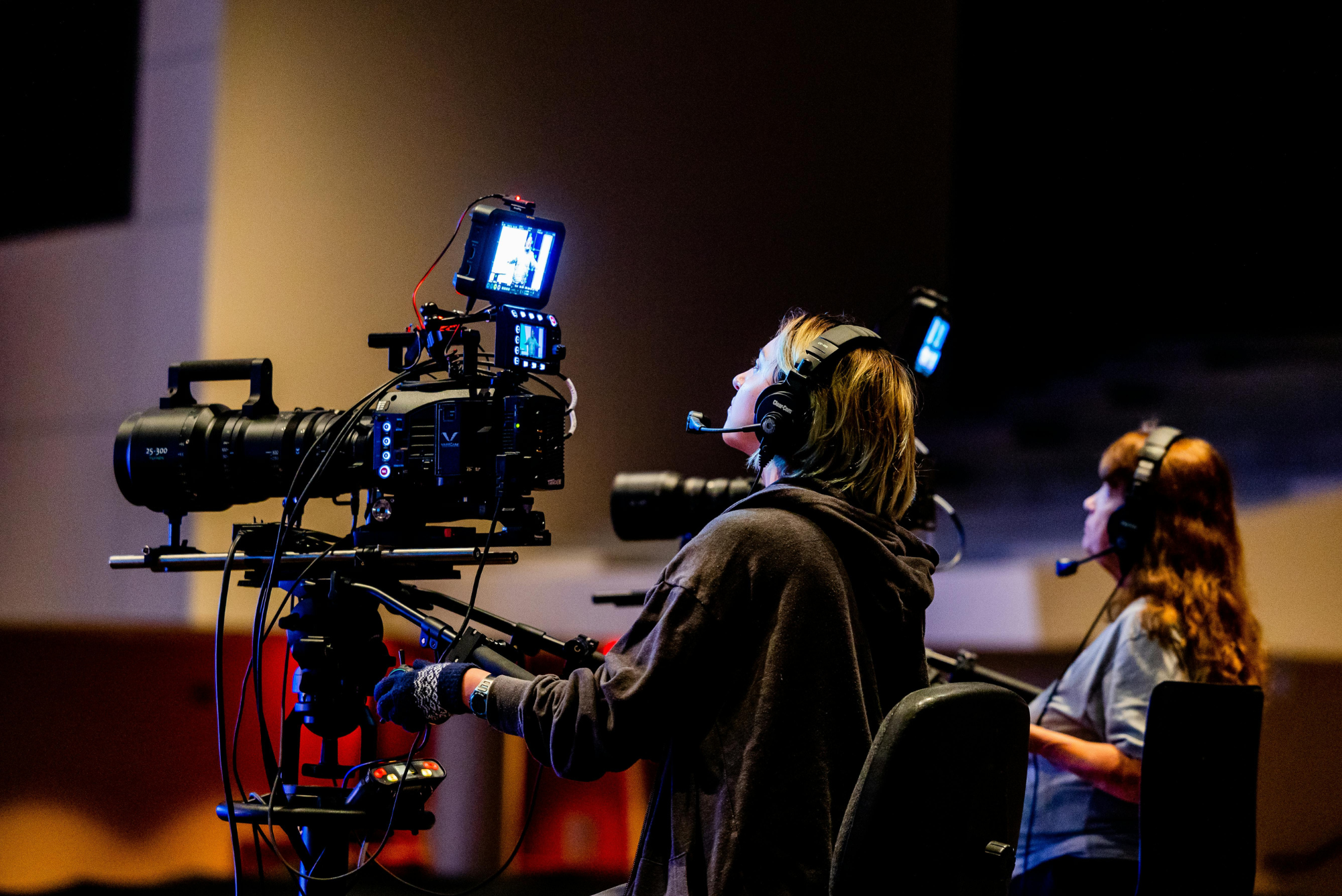 Camera operator and crew member with headsets.