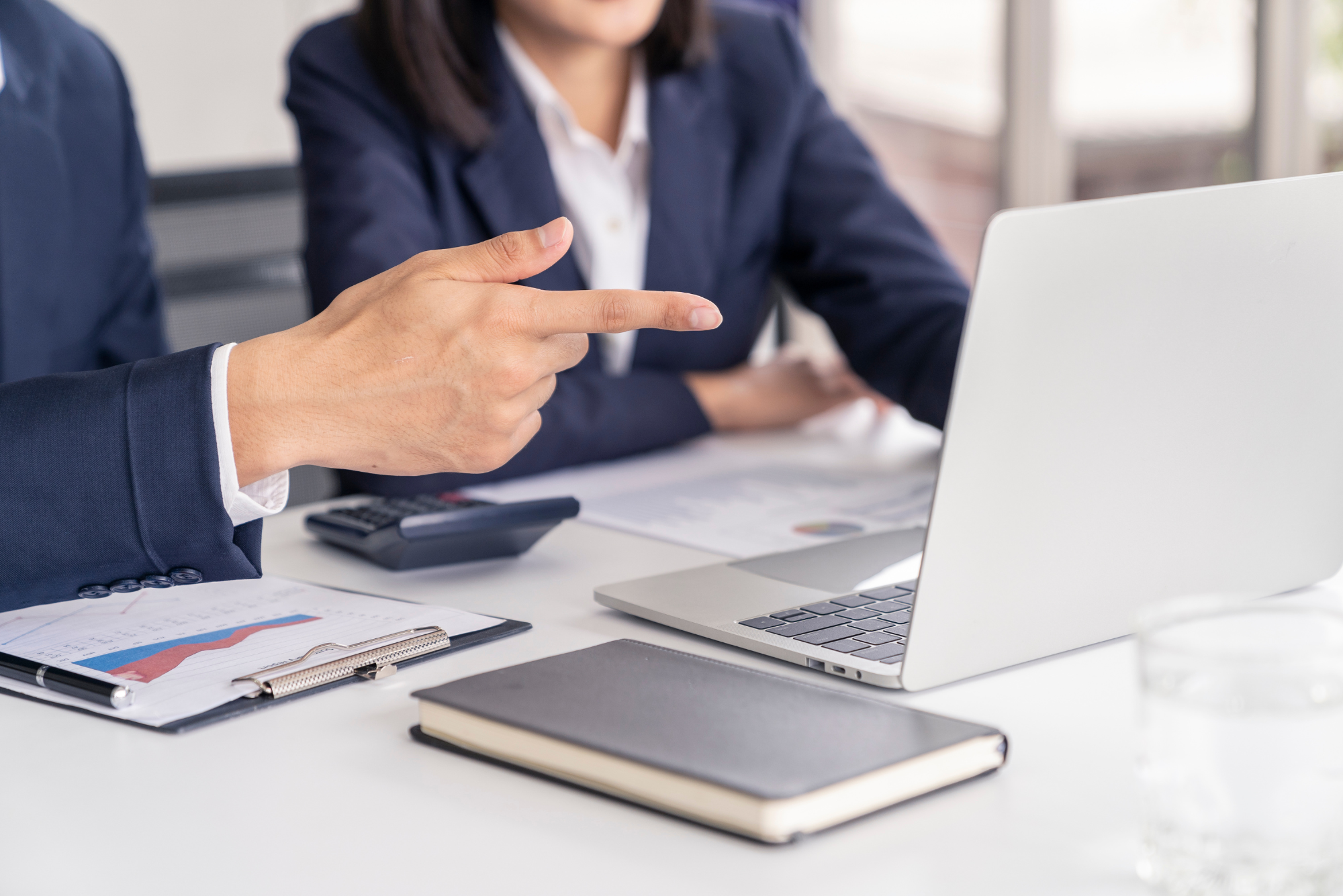 Business professional pointing at a laptop screen.