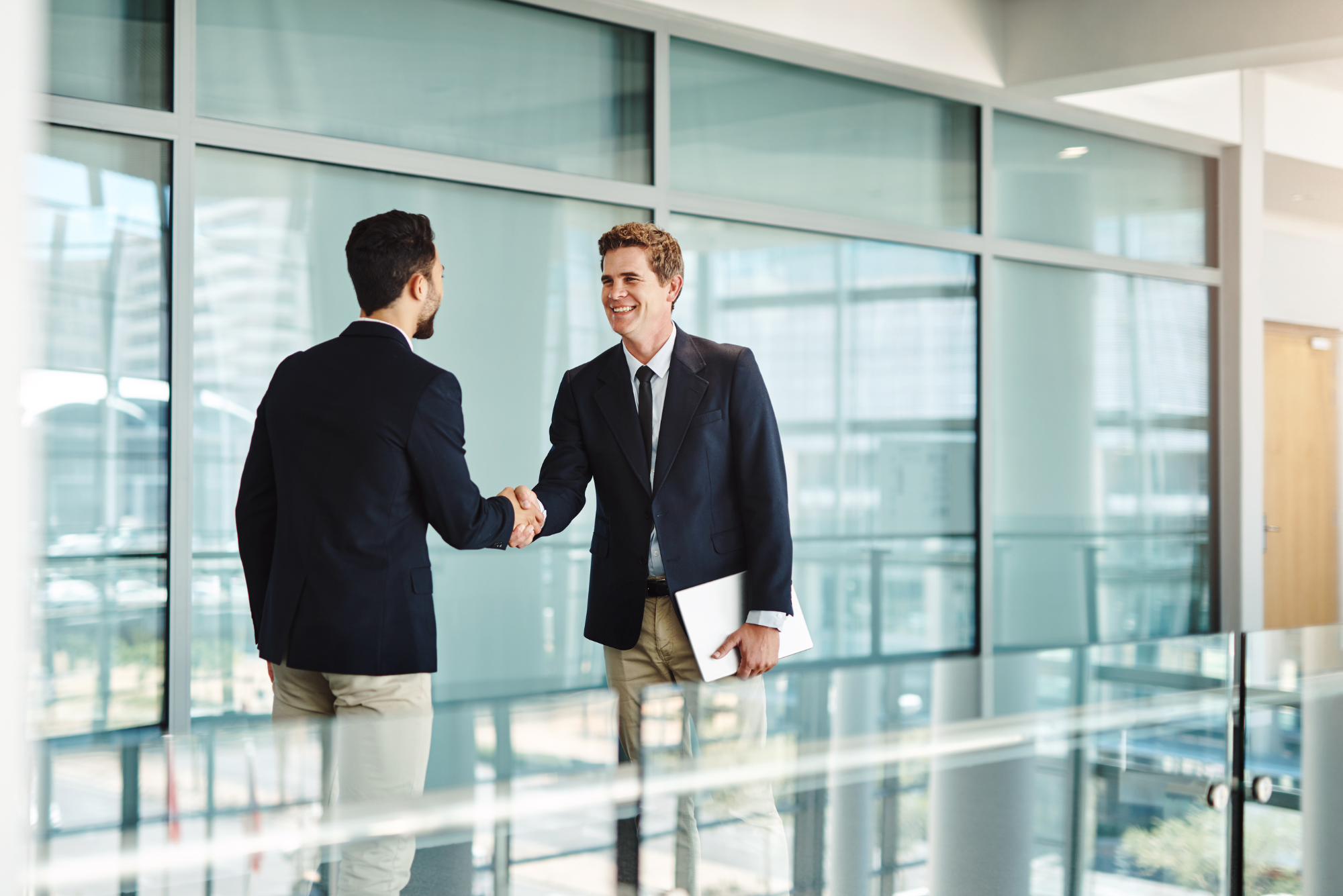 A visitor and host shake hands in the company’s lobby, showing that the best marketing happens on your turf.