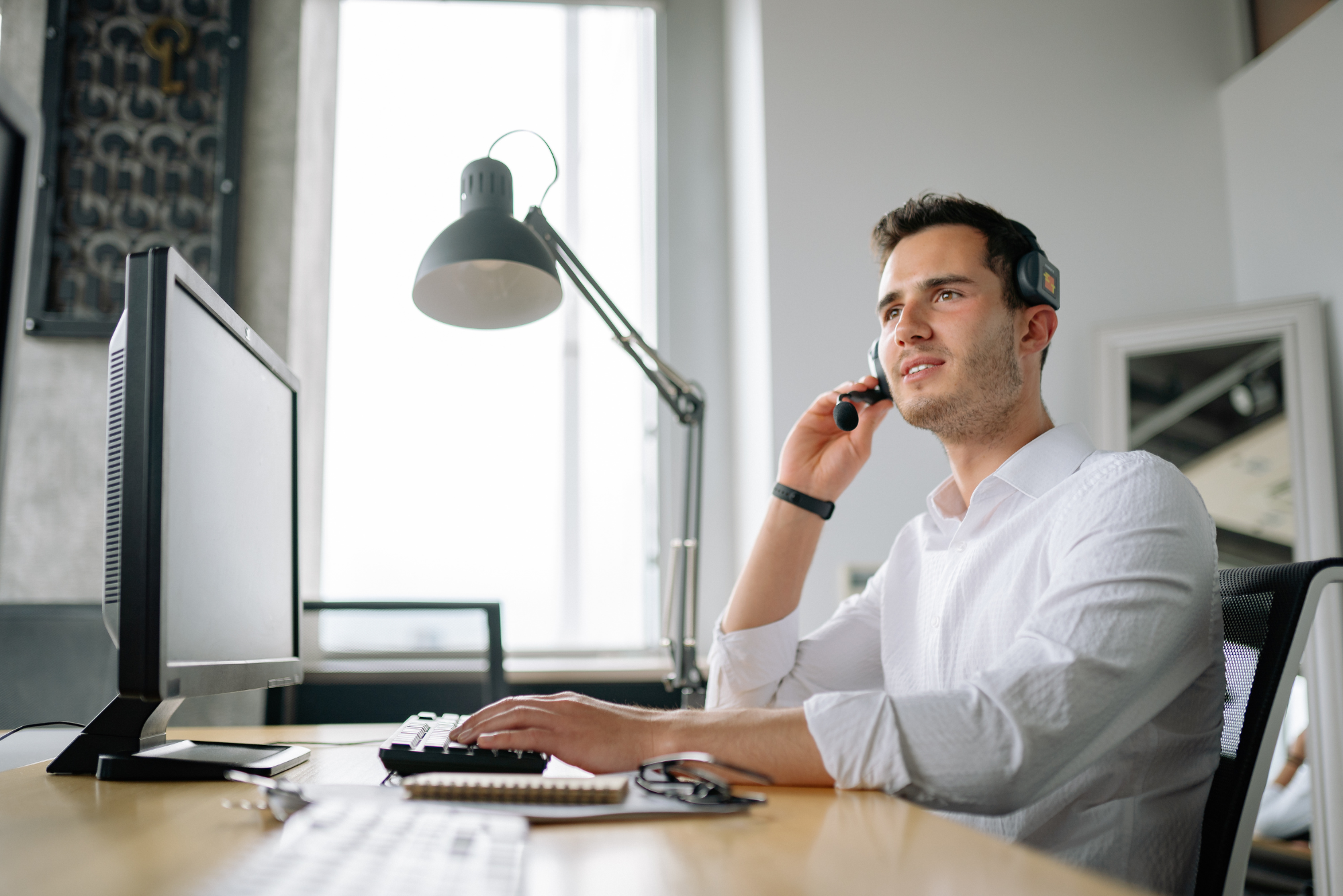 Man in a white shirt making a phone call at his desk.
