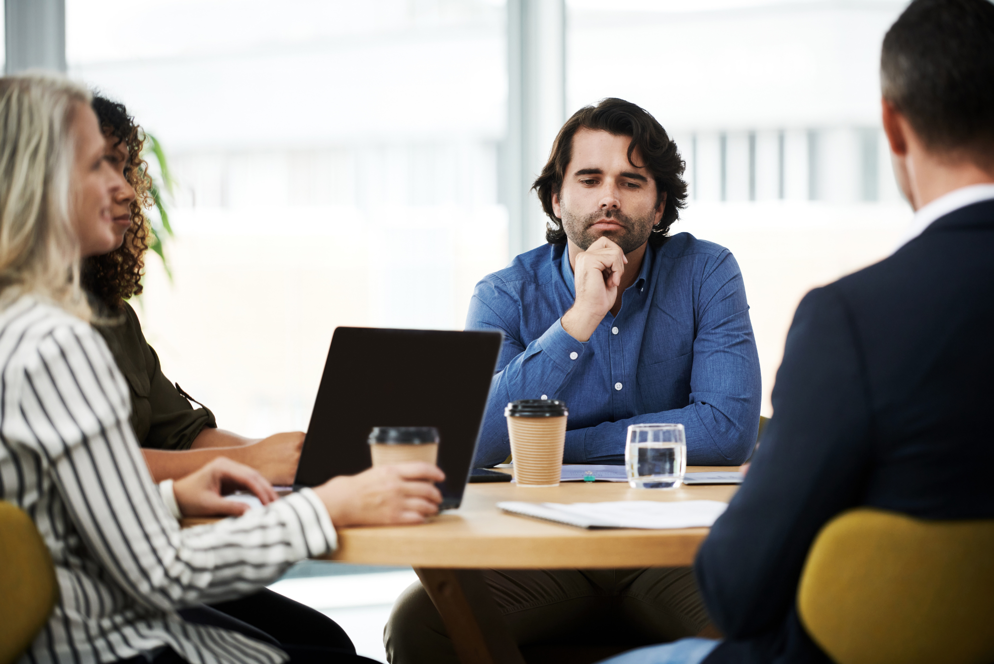 Man with a thoughtful expression listening intently during a business meeting.
