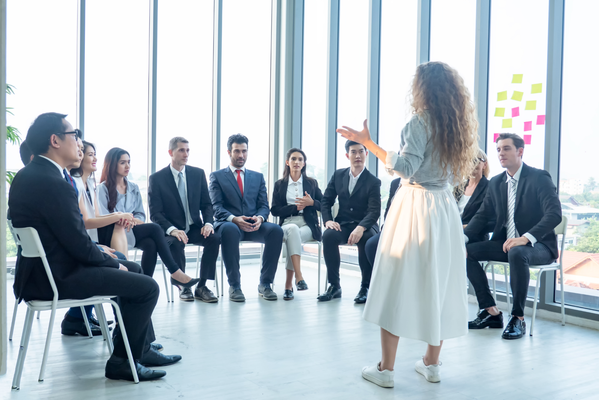 A woman leads a team discussion in a bright modern meeting space.