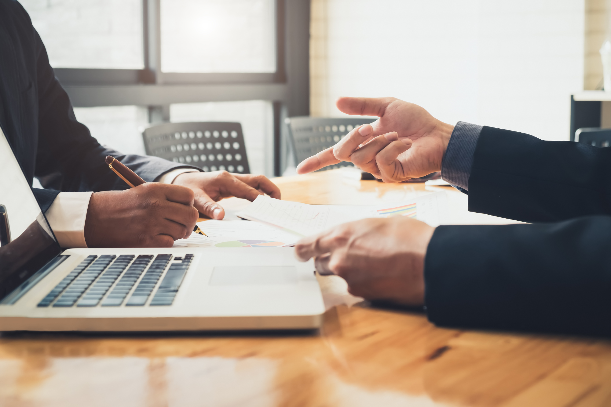 Two professionals review financial charts and documents at a desk.