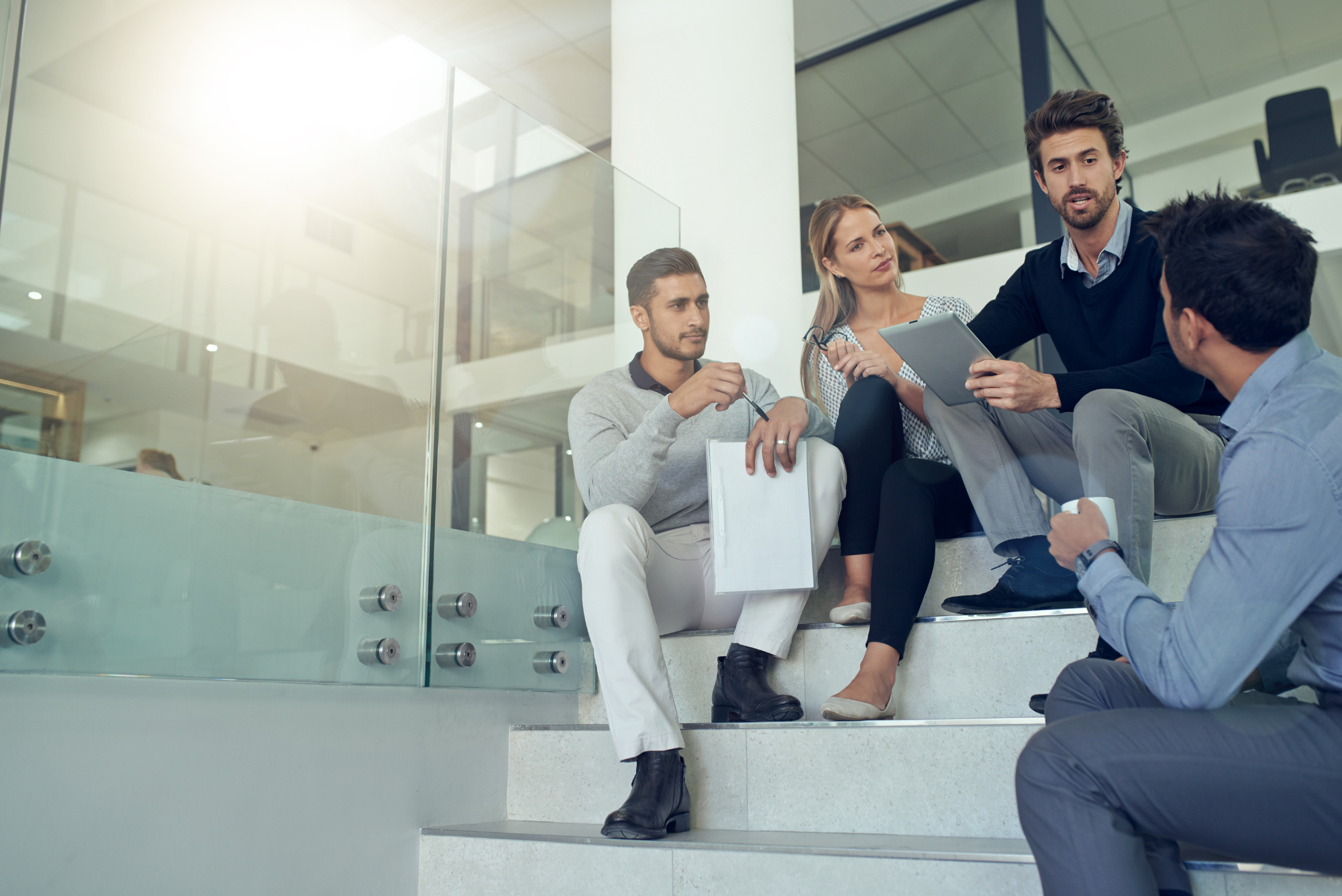 Colleagues having an informal discussion about strategy while sitting on office stairs.