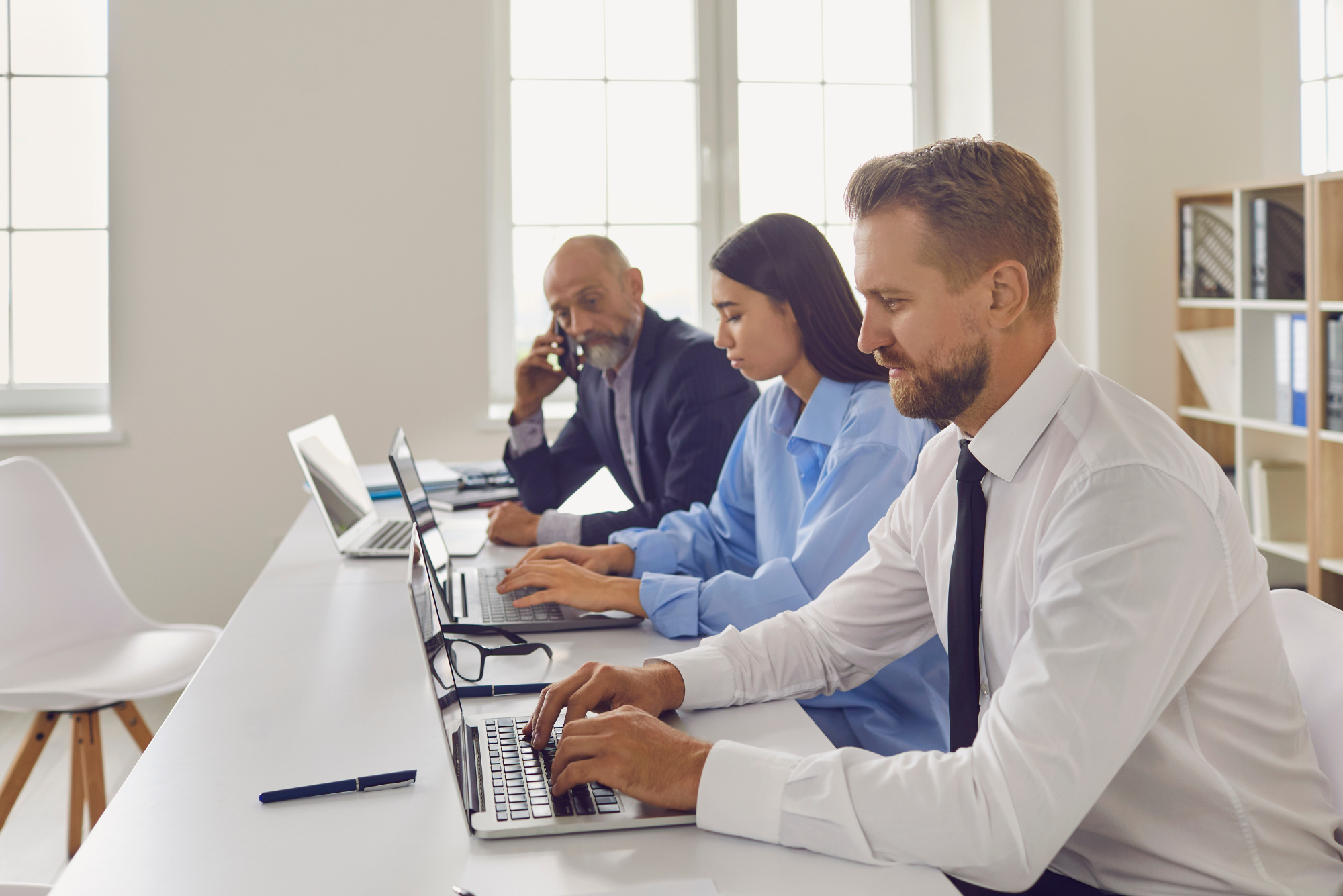 Business professionals working at laptops in an office, illustrating collaboration in a thriving company.