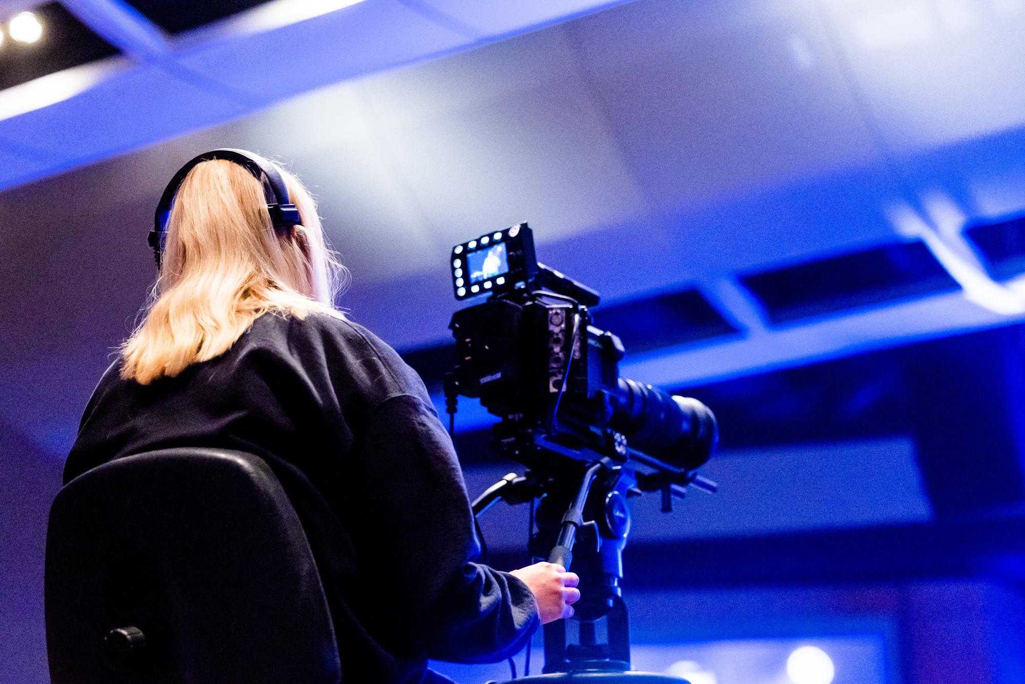 Camera operator filming a live event from behind the camera.